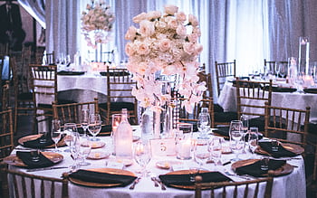 A luxurious wedding dining setup with elegant floral centerpieces and candlelight ambiance. HD wallpaper