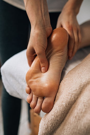 Hands massaging a foot to provide relaxation and promote wellness indoors. HD phone wallpaper