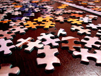 Close-up of colorful jigsaw puzzle pieces scattered on a dark surface. HD wallpaper