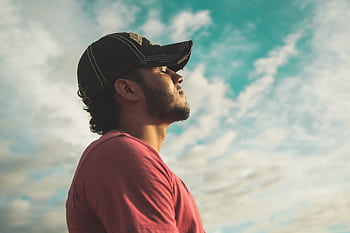 A man enjoys outdoor relaxation and mindfulness beneath a bright, cloudy sky, exuding calm and peace. HD wallpaper