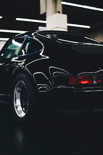 Elegant classic black car with shiny chrome and rear lamp visible in an indoor setting. HD phone wallpaper