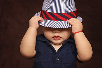 Cute baby in a striped hat covering face, perfect for adorable and playful themes. HD wallpaper