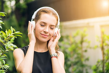 Smiling woman listening to music with heads in sunny garden setting. HD wallpaper