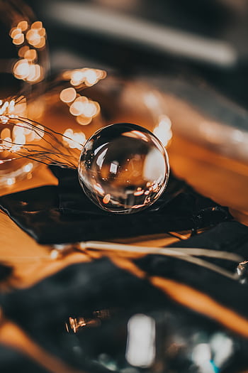 A crystal clear glass sphere with warm bokeh lights creating a festive atmosphere. HD phone wallpaper