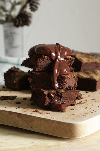 Delicious stack of chocolate brownies drizzled with gooey syrup on a wooden board. HD phone wallpaper