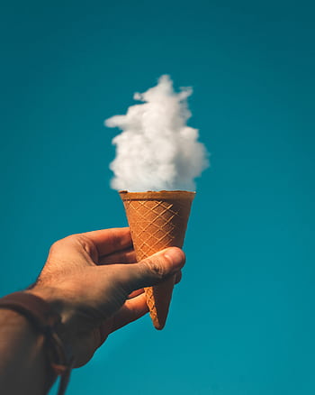 Hand holding an ice cream cone with a cloud effect against a clear sky background. HD phone wallpaper