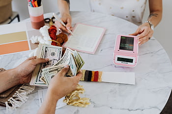A creative workspace featuring a hands-on money counting and budgeting scene. HD wallpaper