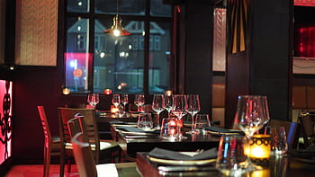 A sophisticated restaurant interior with elegant table setting and ambient candlelight, creating a cozy atmosphere. HD wallpaper