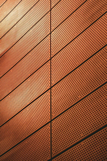 Abstract view of a modern metal wall with geometric patterns and warm lighting. HD phone wallpaper