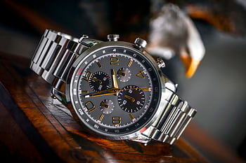 Luxury wristwatch with stainless steel bracelet displayed elegantly on a wooden background. HD wallpaper