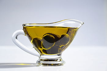 High-resolution of a glass cup filled with olive oil and olives, ideal for culinary themes. HD wallpaper