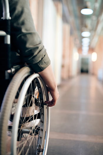 A person in a wheelchair is navigating an indoor hallway, focus on the wheel and hand. HD phone wallpaper
