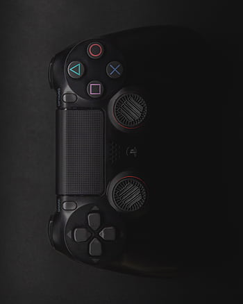 Moody close-up of a black gaming controller in low light with colorful buttons. HD phone wallpaper