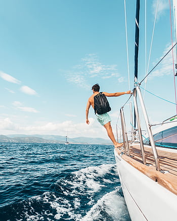 Man sailing in vibrant Greek waters, depicting dom and adventure under clear skies. HD phone wallpaper