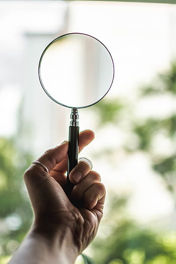 Close-up of a hand holding a magnifying glass on a sunny day outdoors. HD phone wallpaper