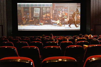 A cozy indoor movie theater showing an animated film to a small audience. HD wallpaper