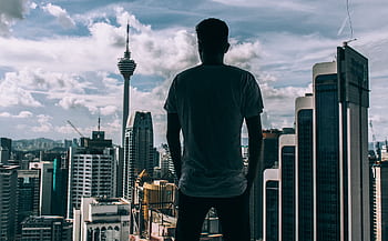A silhouette of a man overlooking the Kuala Lumpur skyline, featuring the iconic KL Tower. HD wallpaper
