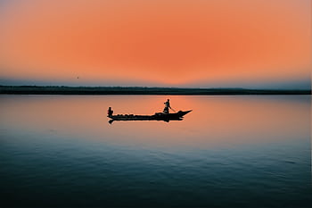 Silhouette of a canoe at sunrise casting reflection on a placid lake. HD wallpaper