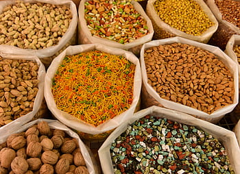 Variety of nuts and spices displayed in bags, showcasing colorful and diverse food options. HD wallpaper