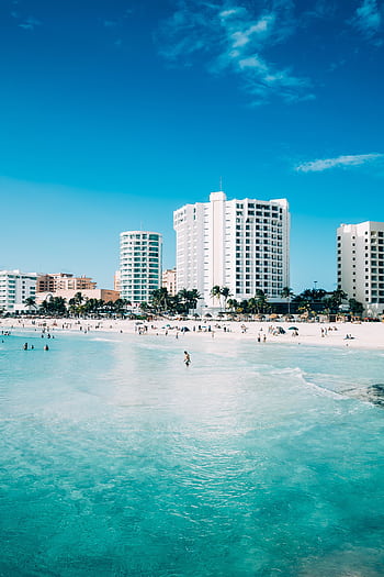 Scenic view of modern hotels along the beachfront in Cancun, Mexico, with clear blue waters. HD phone wallpaper