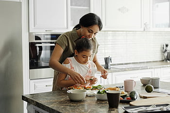 A mom and daughter share a bonding moment while preparing a healthy lunch together in the kitchen. HD wallpaper