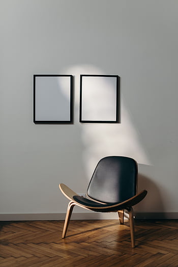 Stylish minimalist interior with black chair and blank frames casting shadows. HD phone wallpaper
