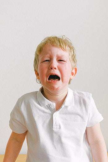A young child crying, wearing a white shirt, showing strong emotions indoors. HD phone wallpaper