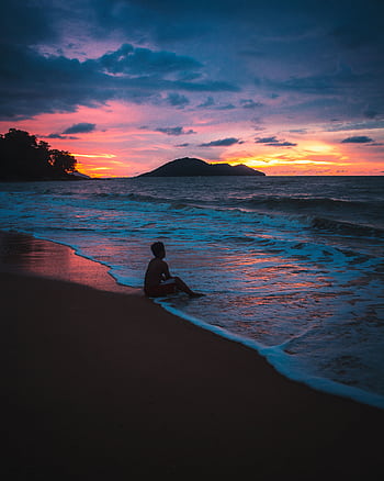 Tranquil beach scene during sunset featuring a solitary silhouette by the ocean. HD phone wallpaper