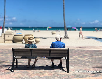 Senior couple sitting on a bench enjoying a sunny day at Hollywood Beach, Florida. HD wallpaper