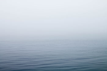 A tranquil scene of mist over a calm lake with gentle ripples on the water surface. HD wallpaper