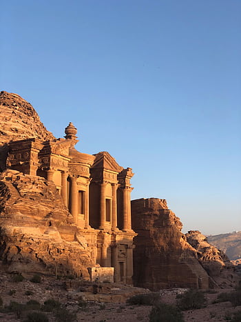 Capture of the ancient Petra Monastery in Jordan illuminated by sunset, showcasing stunning sandstone architecture. HD phone wallpaper