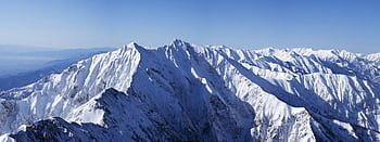 Explore the stunning beauty of snowy mountain peaks under a clear blue sky HD wallpaper