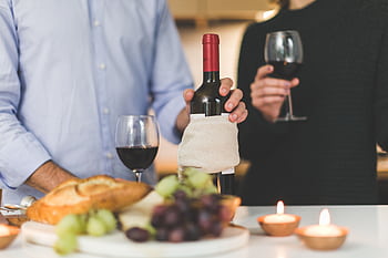 An intimate dinner setting with red wine, bread, and candles, evoking warmth and elegance. HD wallpaper
