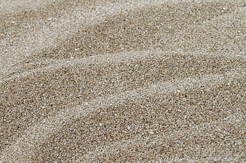 Detailed texture of fine coastal sand captured in a close-up shot. HD wallpaper