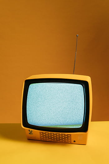 Retro yellow television on orange backdrop with static screen, perfect for vintage themes. HD phone wallpaper
