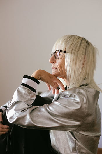 Side view of a pensive elderly woman in a shiny jacket looking thoughtful indoors. HD phone wallpaper