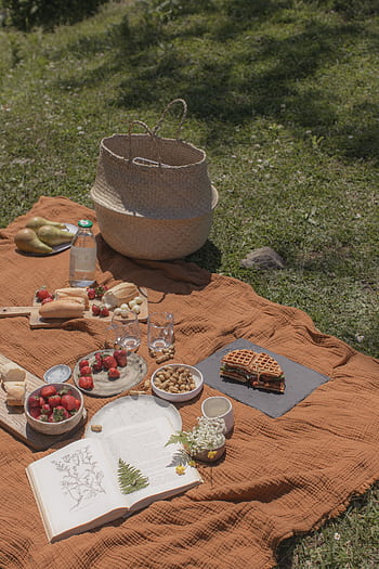 A cozy picnic setup on a blanket with fruits, bread, waffles, and drinks outdoors. HD phone wallpaper