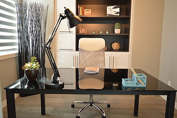 Stylish modern office workspace featuring a black desk, lamp, and white chair with shelving. HD wallpaper