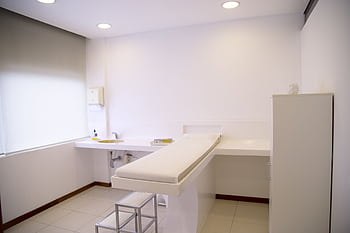 Minimalist white clinic room with examination table and furniture. HD wallpaper