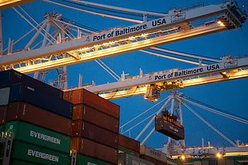 Illuminated cargo cranes at the Port of Baltimore with stacked containers at dusk. HD wallpaper