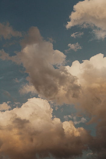 Captivating view of a dramatic cloudscape with varied lighting and textures against a blue sky. HD phone wallpaper