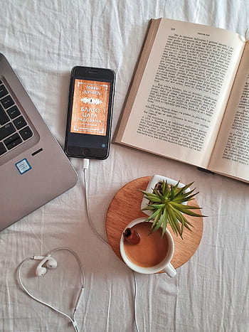 Relaxing workspace flat lay featuring a laptop, book, coffee cup, smart, and plant on a white surface. HD phone wallpaper