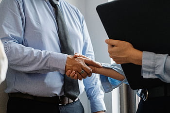Business professionals shaking hands in an office, signaling a successful deal. HD wallpaper