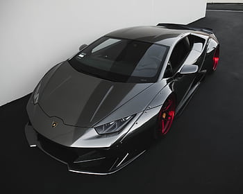 Sleek metallic Lamborghini sports car with vibrant red wheels parked indoors. HD wallpaper