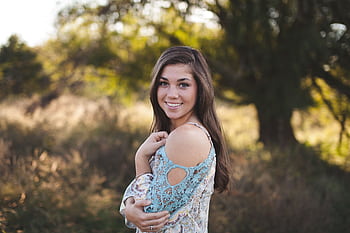 A young woman joyfully smiling in a summer dress, surrounded by nature. HD wallpaper