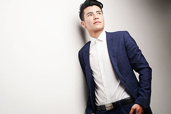 Elegant businessman in a blue suit looking thoughtful, ideal for corporate themes. HD wallpaper