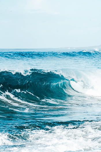 Capture of rolling ocean waves under a pristine blue sky, showcasing nature's beauty. HD phone wallpaper