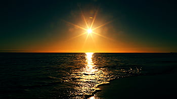 Mesmerizing sunset view over the ocean with a golden horizon, reflecting on calm waves. HD wallpaper