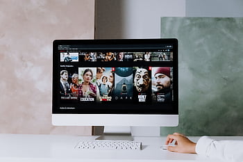 A modern workspace featuring a screen displaying popular streaming series on Netflix. HD wallpaper
