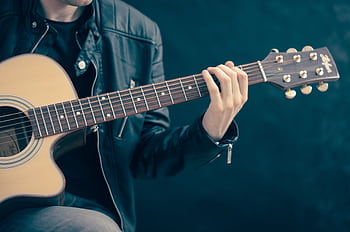 Close-up of a musician playing an acoustic guitar, wearing a leather jacket. HD wallpaper